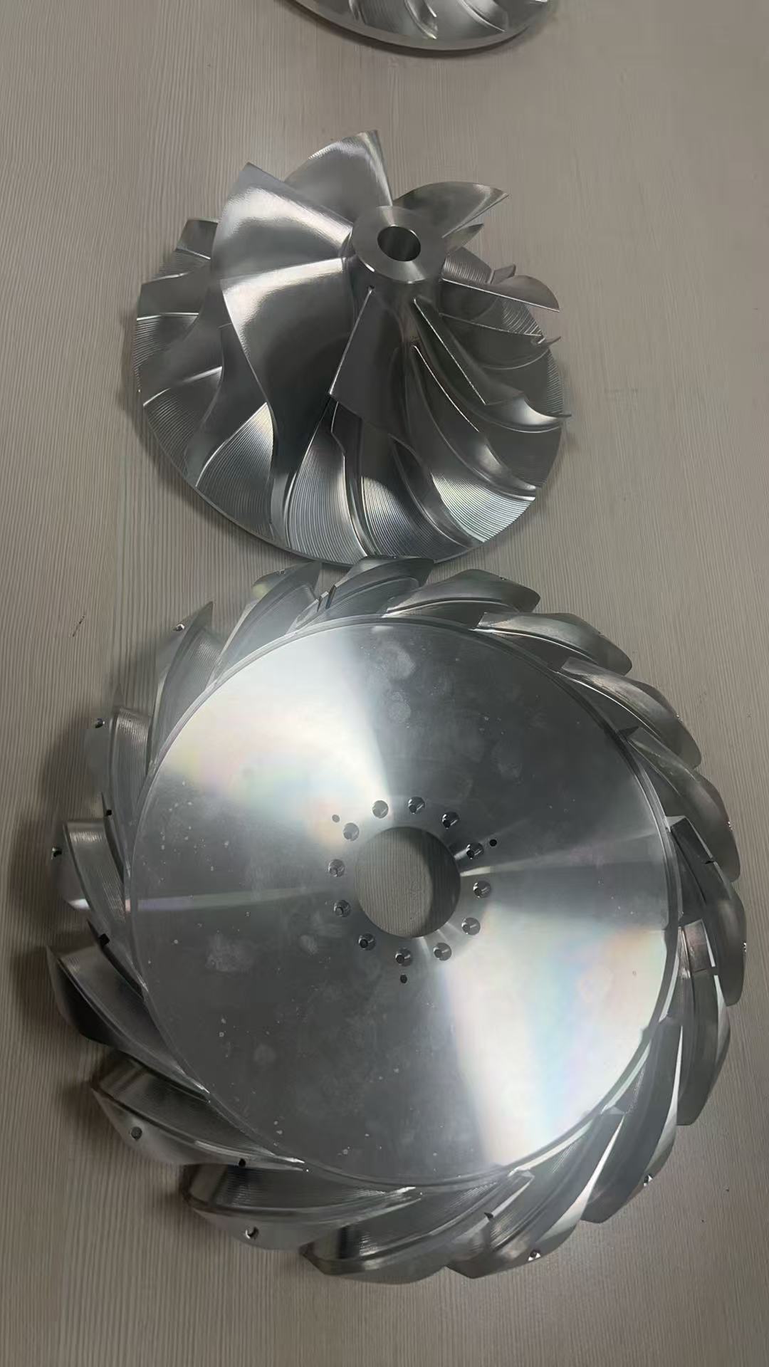 Two finished machined impeller components with complex curved blades